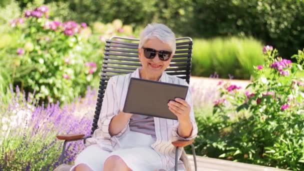 Glückliche Seniorin mit Tablet-PC im Sommergarten — Stockvideo