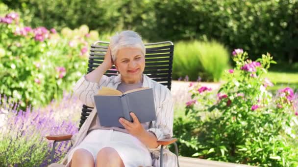 Feliz mujer mayor leyendo libro en el jardín de verano — Vídeos de Stock