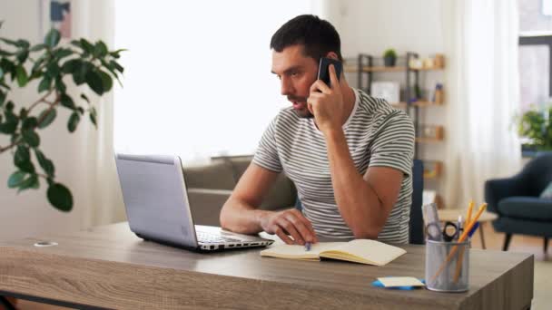 Homme avec ordinateur portable appelant au téléphone au bureau à la maison — Video