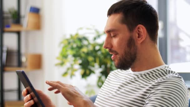 Hombre sonriente con la computadora de la tableta PC en casa — Vídeos de Stock