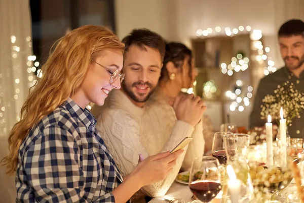 Amigos com celular tendo jantar em casa — Fotografia de Stock