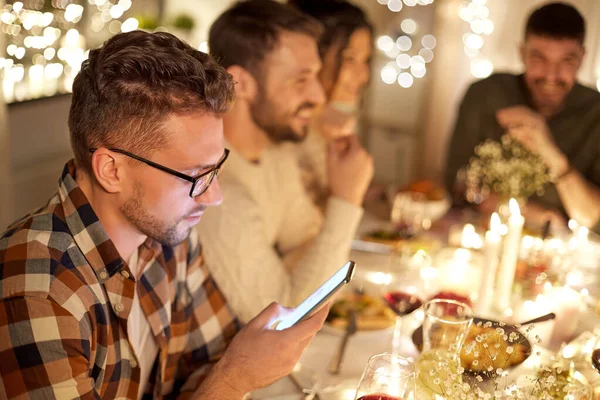 Homem com smartphone no jantar com amigos — Fotografia de Stock