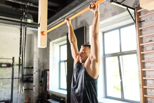 Hombre haciendo ejercicio en la barra y haciendo pull-ups en el gimnasio — Foto de Stock