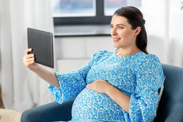 Heureuse femme enceinte avec tablette pc à la maison — Photo