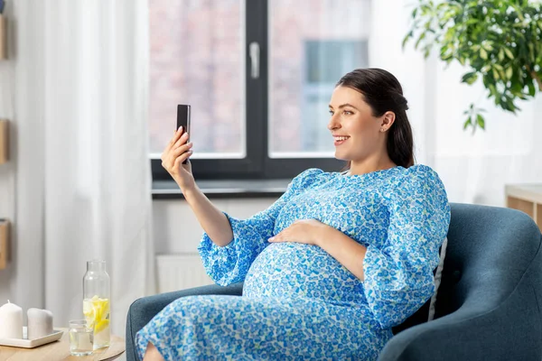 Glückliche Schwangere mit Smartphone zu Hause — Stockfoto