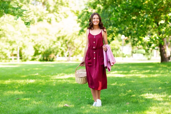 Femme heureuse avec panier pique-nique et couverture au parc — Photo