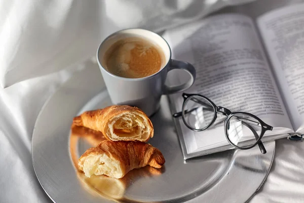 Croissants, tasse de café et réserver au lit à la maison — Photo