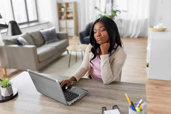 Femme ennuyée avec ordinateur portable travaillant au bureau à la maison — Photo