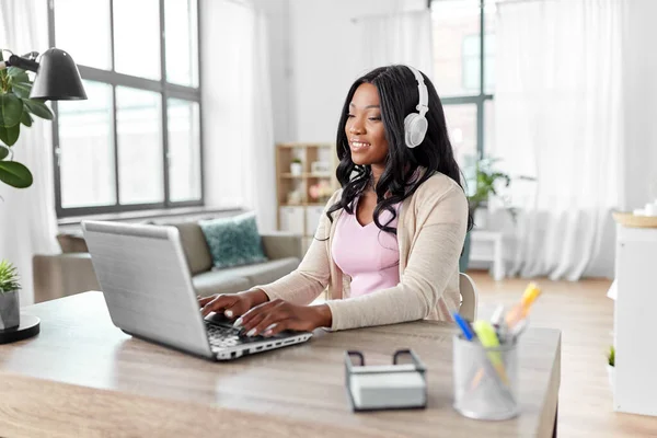 Mujer en auriculares con portátil trabajando en casa — Foto de Stock