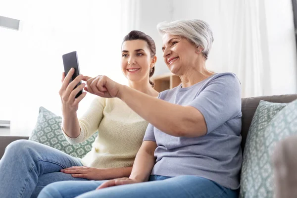 Figlia e madre anziana con smartphone a casa — Foto Stock