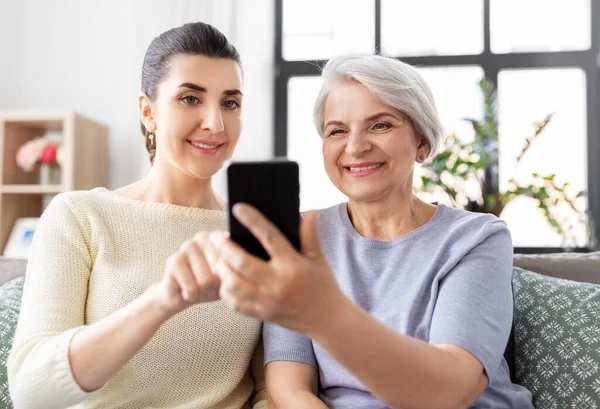 Dochter en senior moeder met smartphone thuis — Stockfoto