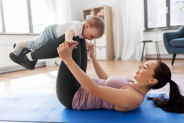 Mãe feliz com pequeno bebê se exercitando em casa — Fotografia de Stock