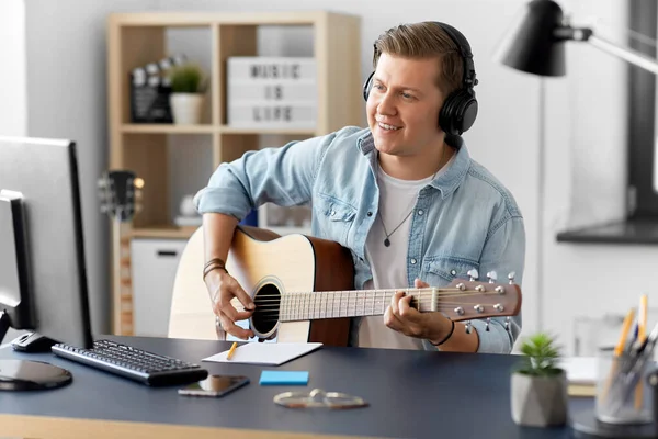 Férfi fülhallgatóban gitározik otthon — Stock Fotó