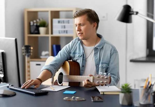 Jeune homme avec guitare et ordinateur à la maison — Photo