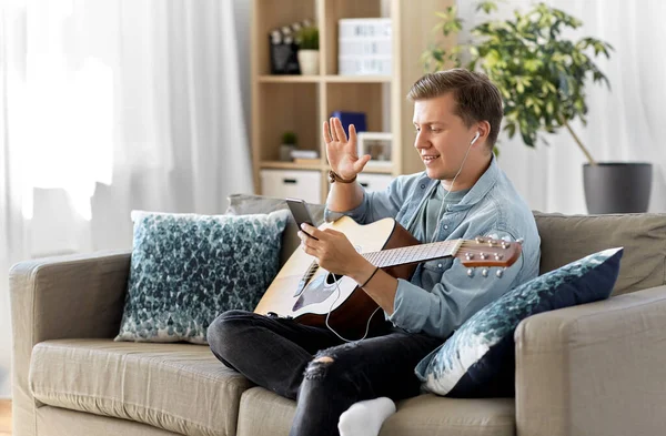 Uomo con chitarra, auricolari e smartphone a casa — Foto Stock