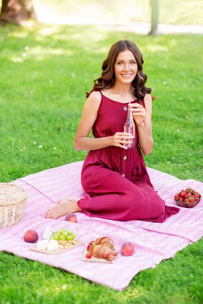 Lycklig kvinna med picknick korg och dricka i parken — Stockfoto