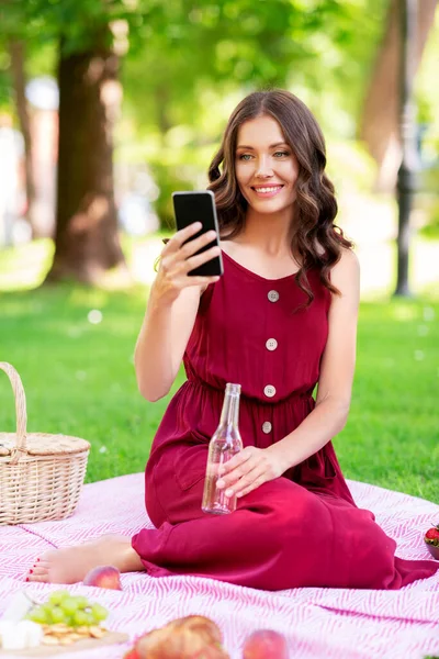 Gelukkig vrouw met smartphone en drinken in park — Stockfoto