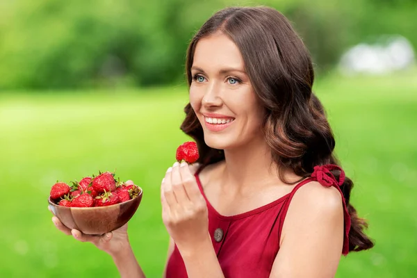 Ευτυχισμένη γυναίκα τρώει φράουλα στο πάρκο του καλοκαιριού — Φωτογραφία Αρχείου