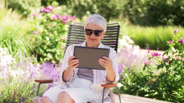 Happy senior woman with tablet pc at summer garden — Stock Video