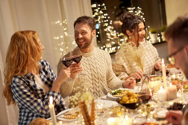 Amigos felizes bebendo vinho tinto na festa de Natal — Fotografia de Stock