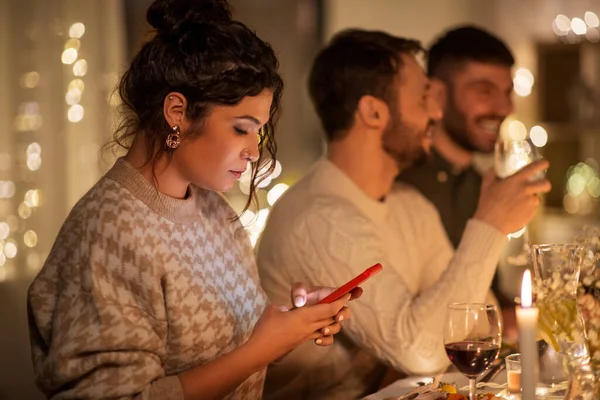 Žena s chytrým telefonem na večeři party s přáteli — Stock fotografie