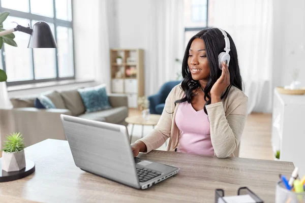 Mulher em fones de ouvido com laptop trabalhando em casa — Fotografia de Stock