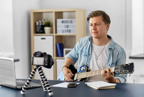 Uomo o blogger con macchina fotografica che suona la chitarra a casa — Foto Stock