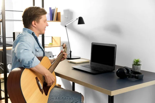 Jovem com laptop e guitarra em casa — Fotografia de Stock