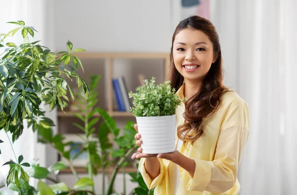 Gelukkig aziatische vrouw met bloem in pot thuis — Stockfoto