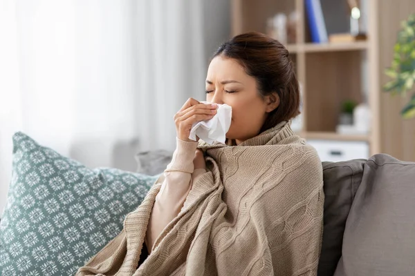 Zieke aziatische vrouw blazen neus met weefsel thuis — Stockfoto