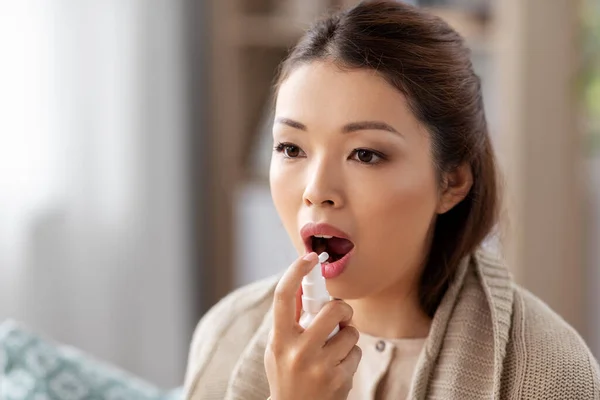 Sick asian woman using oral spray medicine at home — Stock Photo, Image