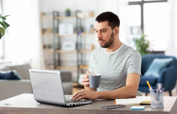 Pria dengan laptop minum kopi di kantor rumah — Stok Foto