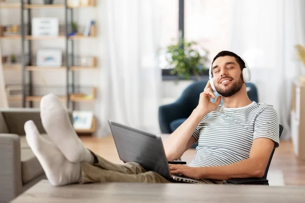 Hombre feliz con portátil y auriculares en casa — Foto de Stock