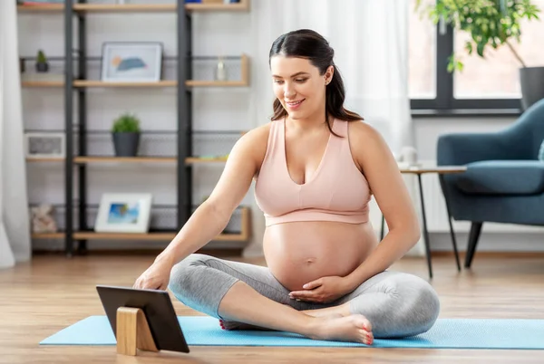 Pregnant woman with tablet pc doing sports at home — Stock Photo, Image