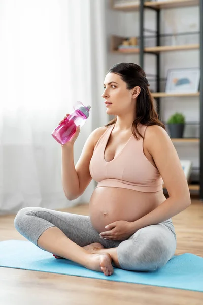 Mulher grávida bebendo água após ioga em casa — Fotografia de Stock