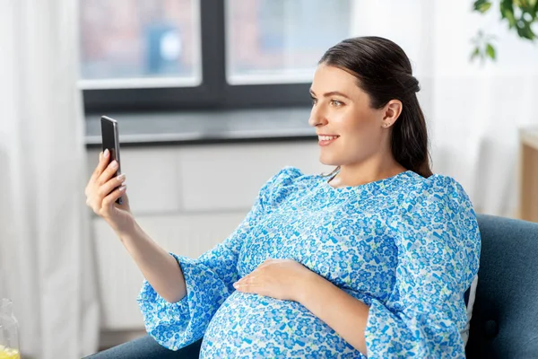 Femme enceinte heureuse avec smartphone à la maison — Photo