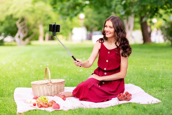 Lycklig kvinna med smartphone tar selfie i parken — Stockfoto