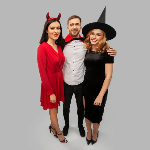 Šťastní přátelé v halloween kostýmy přes šedou — Stock fotografie