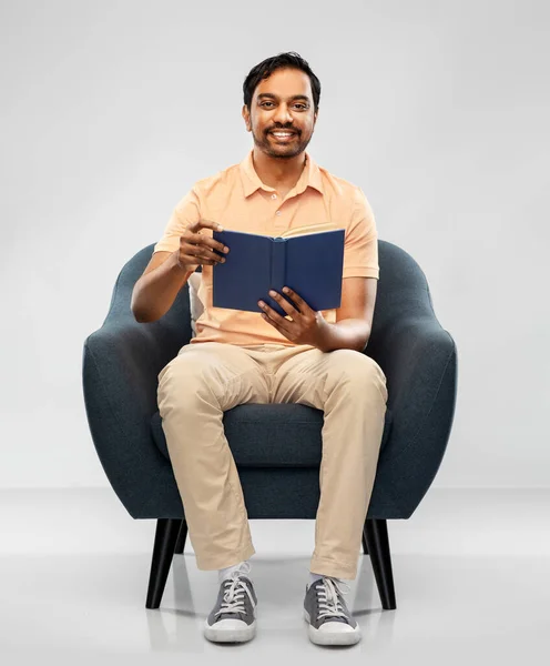 Ευτυχισμένος νεαρός Ινδός άνδρας διαβάζει βιβλίο στην καρέκλα — Φωτογραφία Αρχείου