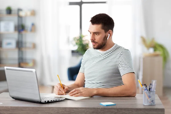 Homem com notebook, fones de ouvido e laptop em casa — Fotografia de Stock