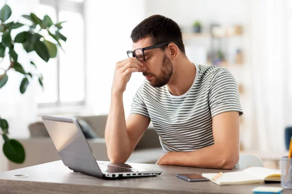 Homem cansado com laptop trabalhando no escritório em casa — Fotografia de Stock