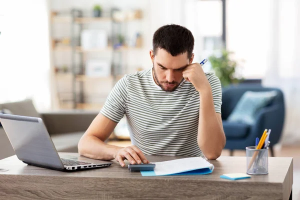 Mann mit Akten und Taschenrechner arbeitet im Homeoffice — Stockfoto