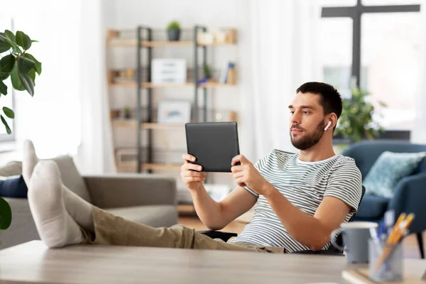 Hombre con tablet PC y auriculares en casa —  Fotos de Stock