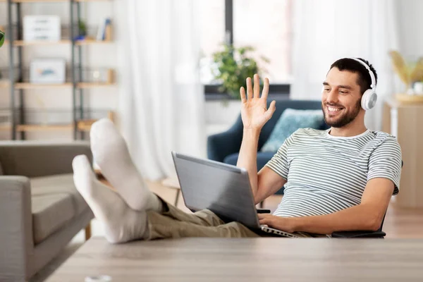 Homme avec ordinateur portable et écouteurs ayant un appel vidéo — Photo