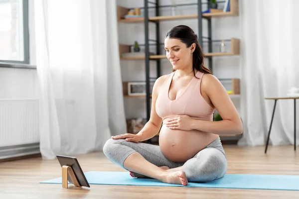 Mulher grávida com tablet pc fazendo esportes em casa — Fotografia de Stock