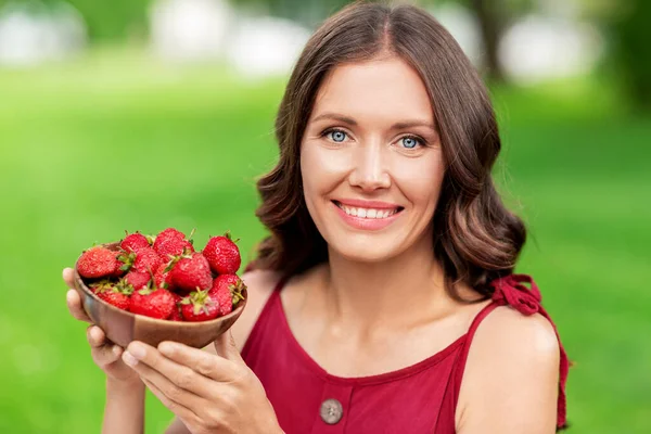 Gelukkig vrouw eten aardbei in de zomer park — Stockfoto