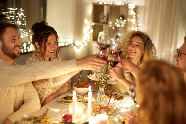 Amigos felices bebiendo vino tinto en la fiesta de Navidad — Foto de Stock