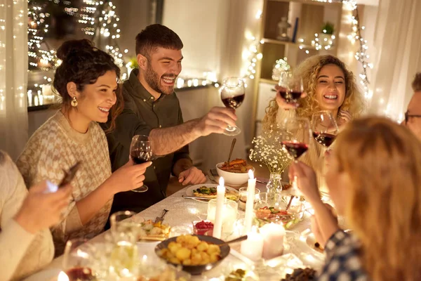 Amigos felices bebiendo vino tinto en la fiesta de Navidad — Foto de Stock