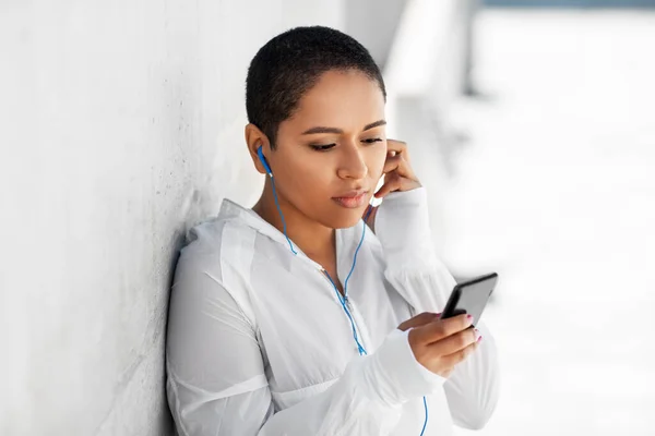 Africká americká žena se sluchátky a telefonem — Stock fotografie