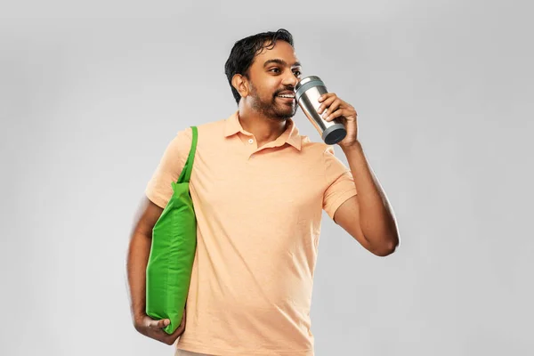 Man met voedsel in zak en tuimelaar of thermo cup — Stockfoto